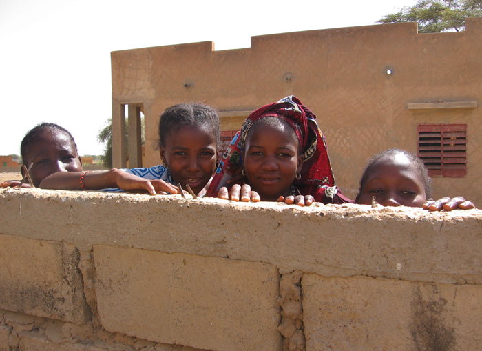 Senegalese school children looking over concrete wall