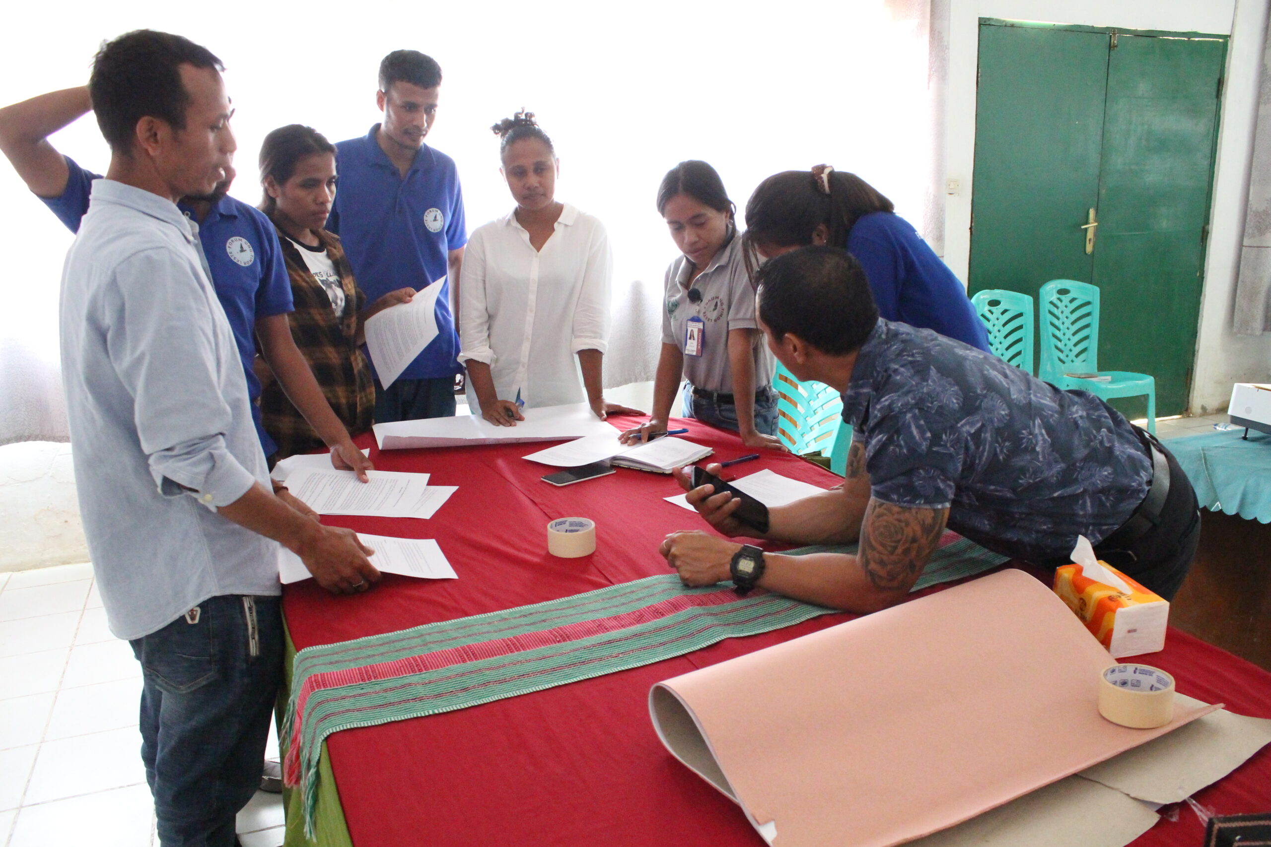 Joao Soares leaning over a table, leading a training on "unconscious bias" with the gender focal points (men and women, gathered around a table with notebooks).